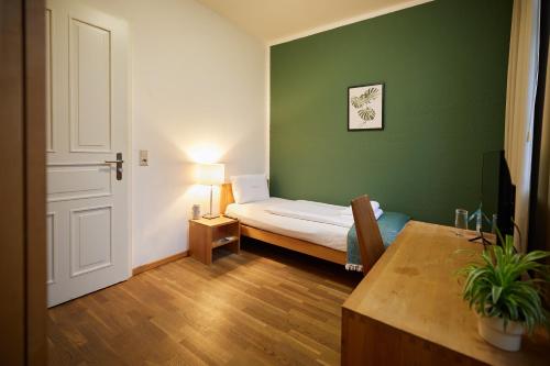 a small green room with a bed and a table at ahead burghotel in Lenzen