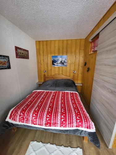 uma cama num quarto com um edredão vermelho em Les Mélèzes em Saint-Chaffrey