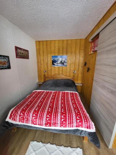 a bed in a room with a red comforter at Les Mélèzes in Saint-Chaffrey