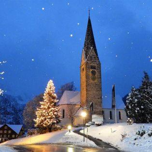 a church with a clock tower in the snow at Appartement 412 Kunners Oostenrijk in Mittelberg
