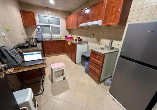 Happy Living Hostel في دبي: مطبخ بدولاب خشبي وثلاجة