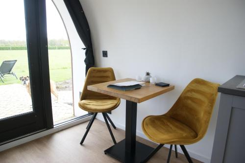 een tafel en 2 stoelen in een kamer met een raam bij Tiny Wellnesslodge Wulp met sauna in Dalerveen
