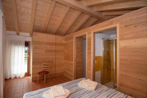 a bedroom with wooden walls and a bed and a shower at Bel Sass in Piuro