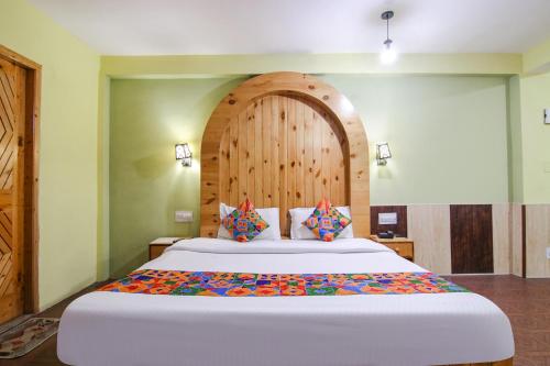 a bedroom with a large bed with a wooden headboard at FabHotel River Bank in Vashisht