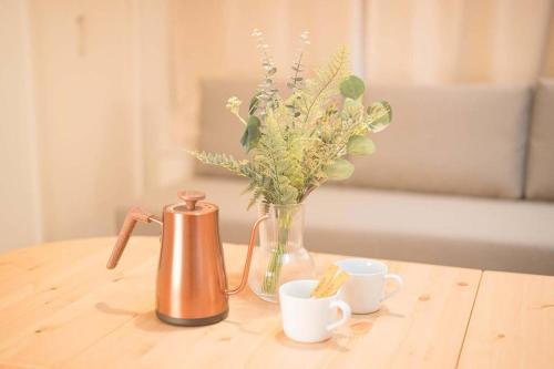 un jarrón de flores y dos tazas en una mesa en Lido East Shinagawa　, en Tokio