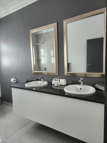 a bathroom with two sinks and two mirrors at La Chambre Manor House in Nelspruit
