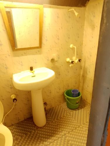a bathroom with a white sink and a green bucket at Jasmine Beach Resort in Morjim