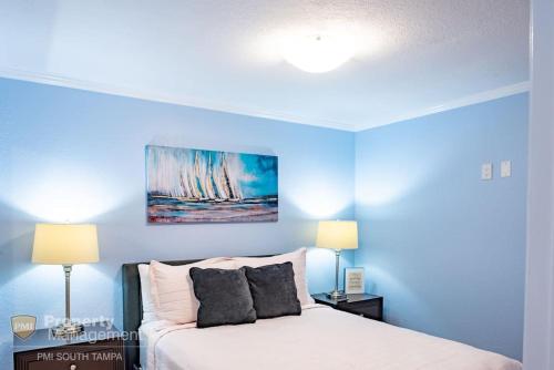 a bedroom with blue walls and a bed with two lamps at Bay Dreamer in Tampa