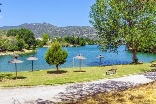 un parque con sombrillas y un banco junto a un lago en Camping les Rives du Lac de Vinça en Vinça