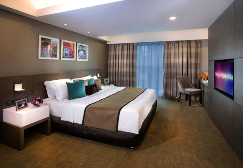um quarto de hotel com uma cama grande e uma televisão em Ascott Sentral Kuala Lumpur em Kuala Lumpur