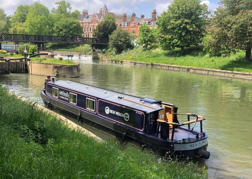 a boat traveling down a river in a city at Cambridge Narrowboats - Beautiful New Moon Narrowboat in Cambridge