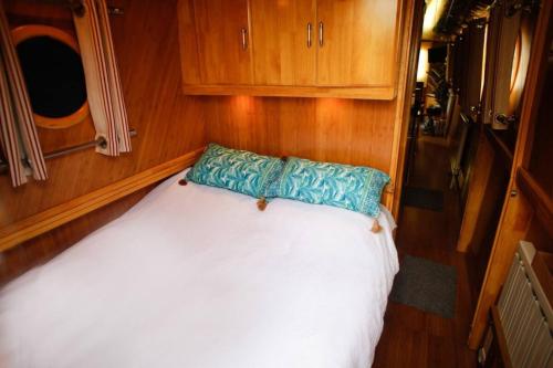 a bedroom with a white bed with a blue pillow at Beautiful New Moon Narrowboat in Cambridge