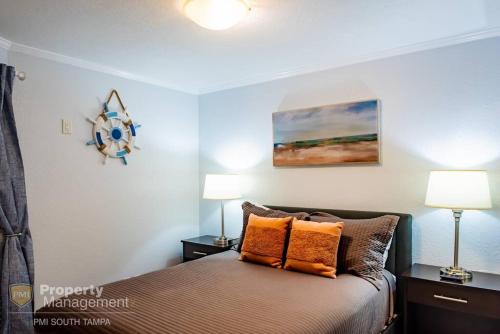 een slaapkamer met een bed met 2 lampen en een schilderij bij Bay View Rendezvous in Tampa