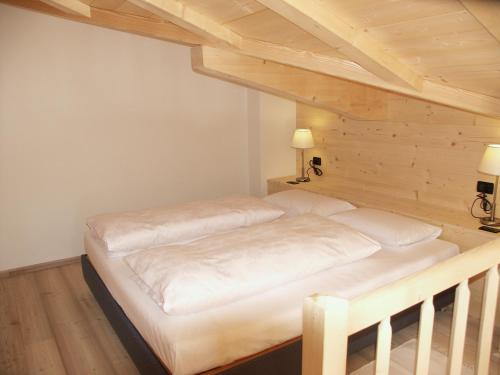duże łóżko w pokoju z drewnianymi sufitami w obiekcie Chalet da mont Resciesa w mieście Ortisei