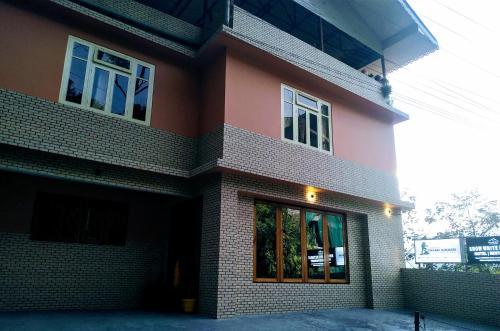ein rotes Backsteinhaus mit einem großen Fenster in der Unterkunft snow white retreat hotel and restaurant in Gangtok