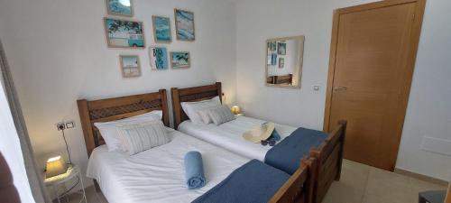 een slaapkamer met 2 bedden met witte lakens en blauwe kussens bij Villa Dinateli, Salinas Golf in Caleta De Fuste