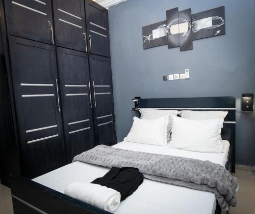 a bedroom with two beds with black cabinets and white pillows at Appart ELRESIDANCIEL Palmiers 2 in Douala
