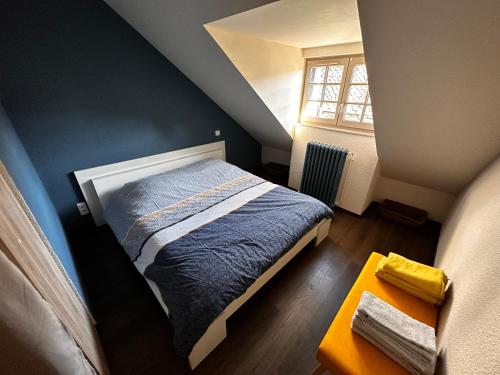 ein kleines Schlafzimmer mit einem Bett und einem Fenster in der Unterkunft La Maison aux Volets Bleus 3ème Étage in Vic-sur-Cère