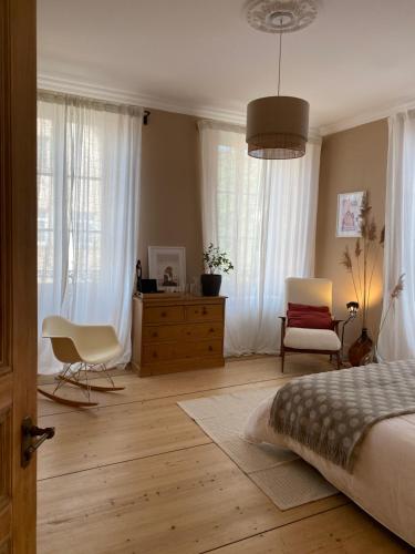 sypialnia z łóżkiem, komodą i oknami w obiekcie Les chambres de la Villa Oberlin w mieście Beblenheim
