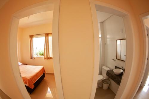 a bedroom with a bed and a bathroom with a mirror at Residencial Beija-Flor in Palhoça