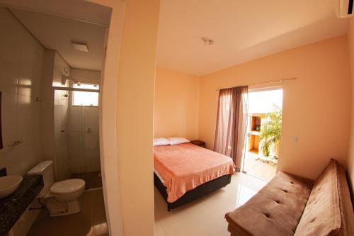 a bedroom with a bed and a bathroom with a toilet at Residencial Beija-Flor in Palhoça