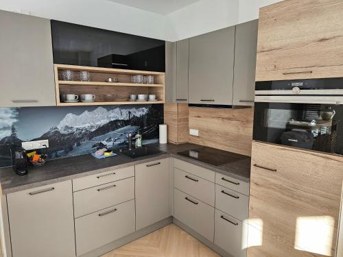 a kitchen with white cabinets and a mountain picture on the wall at Rocks Graz in Graz