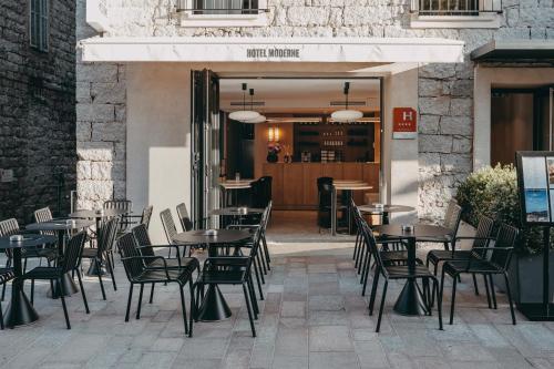 een restaurant met tafels en stoelen voor een gebouw bij Hotel Moderne in Porto-Vecchio