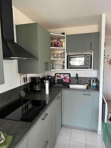 une cuisine avec un évier et un micro-ondes dans l'établissement Appartement face à la mer canet en Roussillon, à Canet