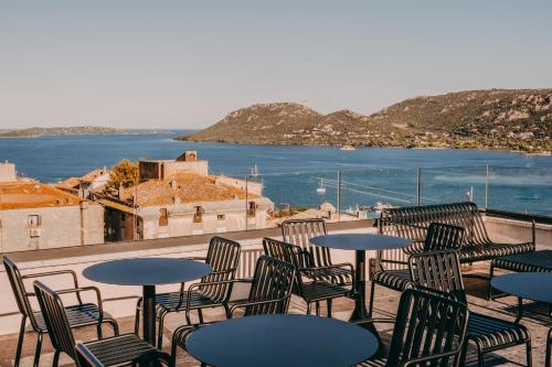 a group of tables and chairs on a balcony with the water at Hotel Moderne in Porto-Vecchio