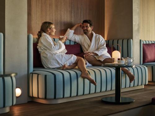 mężczyzna i kobieta siedzący na łóżku w obiekcie Straubinger Grand Hotel Bad Gastein w mieście Bad Gastein