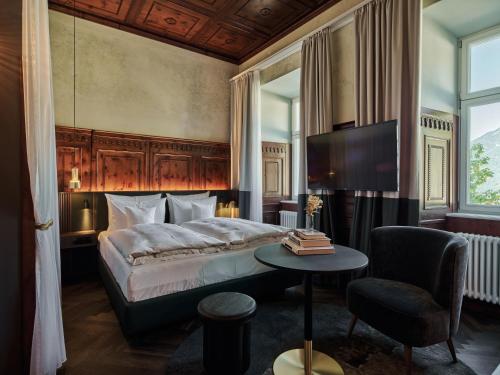 1 dormitorio con cama, mesa y TV en Straubinger Grand Hotel Bad Gastein, en Bad Gastein