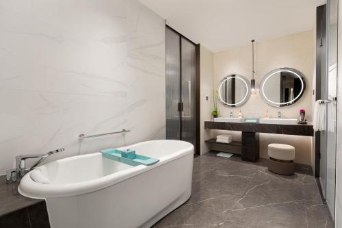 a white bathroom with a tub and two mirrors at Crowne Plaza Jiangmen Binjiang by IHG in Jiangmen
