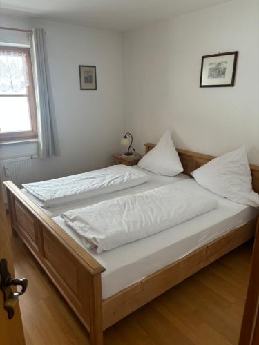 a bed with white sheets and pillows in a bedroom at Sonnenblick in Bad Tölz
