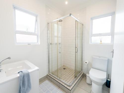 uma casa de banho com um chuveiro, um WC e um lavatório. em Secure, Peaceful Modern Cottage for Two em Durban