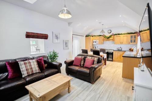 a living room with two leather couches and a kitchen at Superb Location - 'The Annexe' - at Ty Moel Isaf in Amlwch