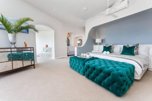 a bedroom with a large bed with a blue tufted couch at Lalaria Ocean Villa suite 5 in Ballito