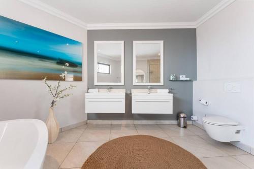 a bathroom with two sinks and two mirrors at Lalaria Ocean Villa suite 5 in Ballito