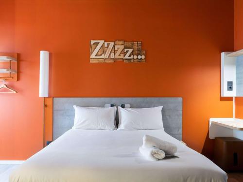 ibis budget Madrid Aeropuerto في مدريد: غرفة نوم بسرير كبير بجدار برتقالي