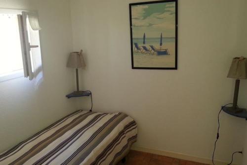 ein Schlafzimmer mit einem Bett mit zwei Lampen an der Wand in der Unterkunft Villa vacances N°23 à 100 mètres de la plage in Saint-Cyprien
