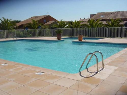 einen Pool mit blauem Wasser in einem Resort in der Unterkunft Villa vacances N°23 à 100 mètres de la plage in Saint-Cyprien