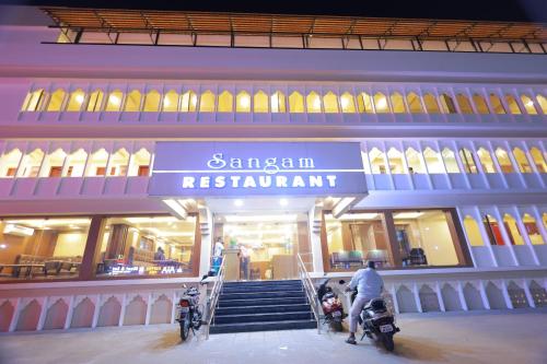 two people on motorcycles in front of a building at Hotel Sangam in Kanyakumari