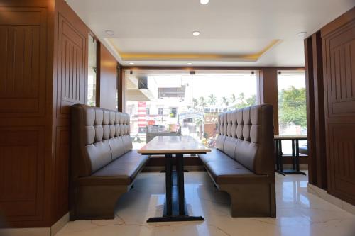 a restaurant with a table and benches in a room at Hotel Sangam in Kanyakumari
