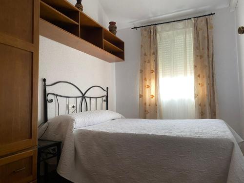 1 dormitorio con cama blanca y ventana en Apartamentos Fuente La Raja, en La Iruela
