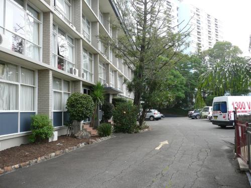 a building with a van parked next to a street at Parramatta City Motel in Sydney