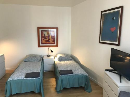 une chambre avec deux lits et une télévision à écran plat dans l'établissement AparisAppart, à Pantin