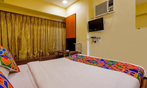 a hotel room with a bed and a television at FabExpress Jayshree - Nr Mumbai International Airport in Mumbai