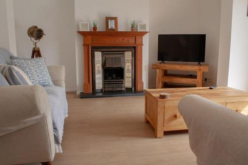 a living room with a television and a fireplace at East Wittering fun, sun and sea in West Wittering