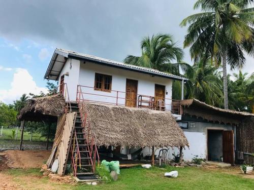 a house with a thatch roof and a staircase at Cute house with salt lake view in Kandakuli