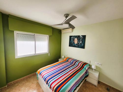Dormitorio verde con cama y ventana en ÁTICO ZONA VENEZIOLA, LA MANGA, en La Manga del Mar Menor