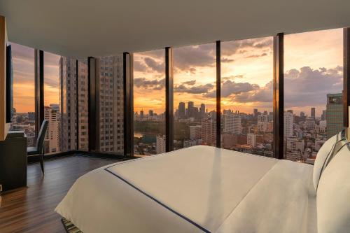 a bedroom with a view of a city at The Continent Hotel Sukhumvit - Asok BTS Bangkok by Compass Hospitality in Bangkok